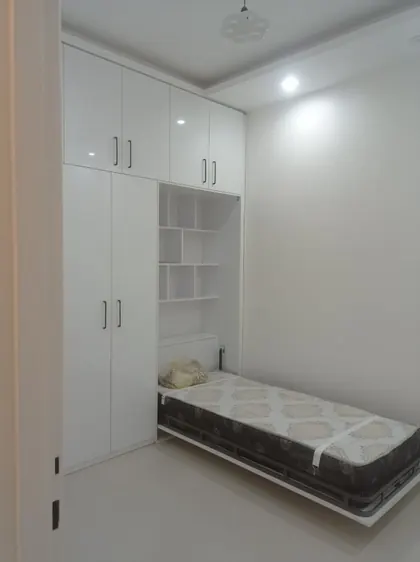تخت تاشو کم‌جا در کنار کمد دیواری سفید